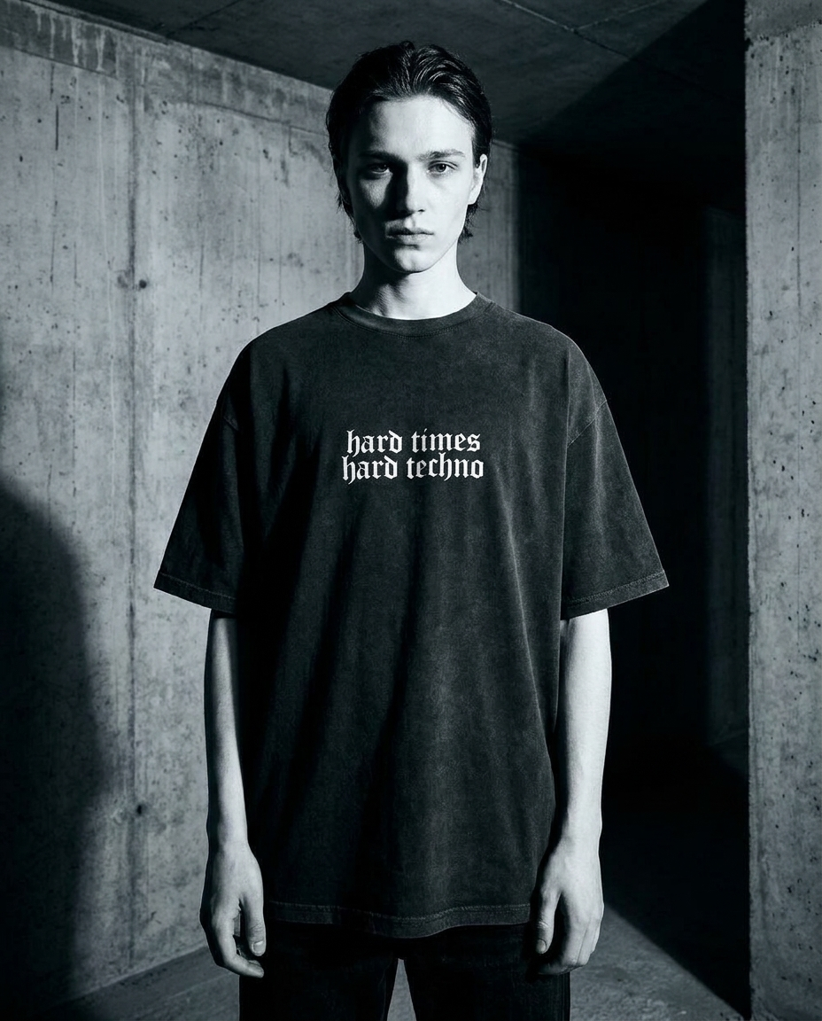 Model wearing the black Hard Times Hard Techno oversized shirt, front view, brutalist industrial rave photoshoot